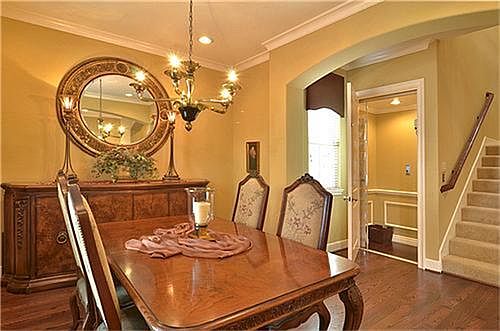 Elegant formal dining room features hardwood flooring, a chandelier, archway entry and crown molding.