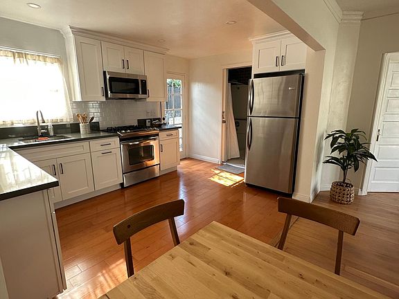 kitchen, featuring new cabinets, stone countertops, hardwood floors, and stainless steel appliances