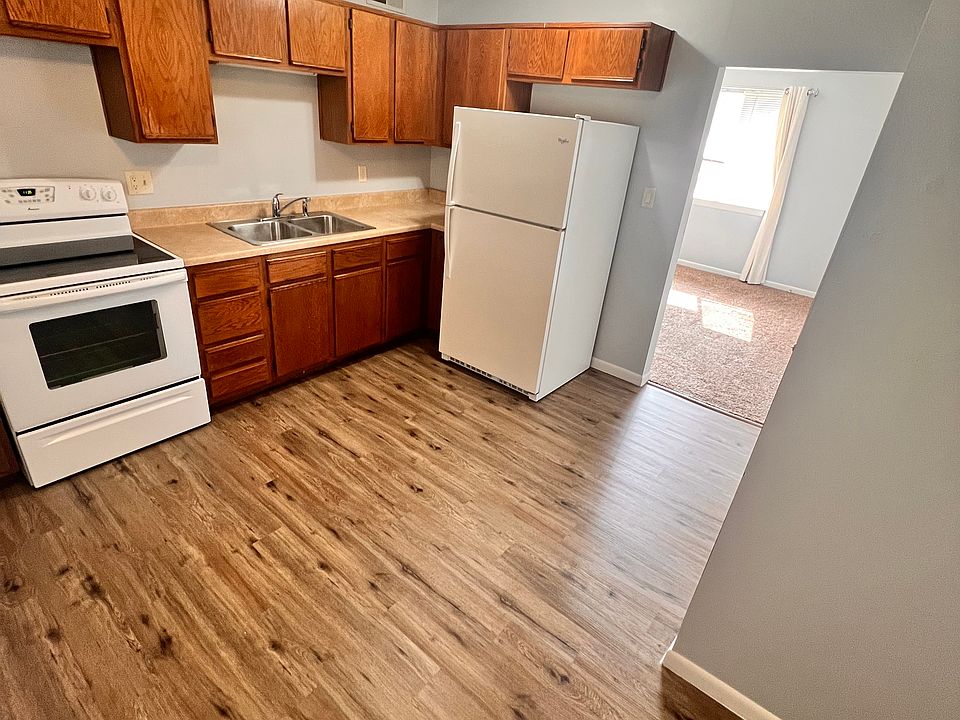 kitchen view of cabinetry and appliances, living room in distance.