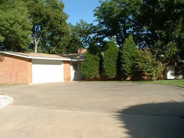 Large lovely trees fill the property and line the front of the house.