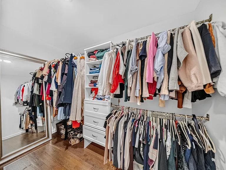 Generous Walk-In Closet with Custom Built-in Shelving, drawers, and double hung rod space, plus a full length mirror!