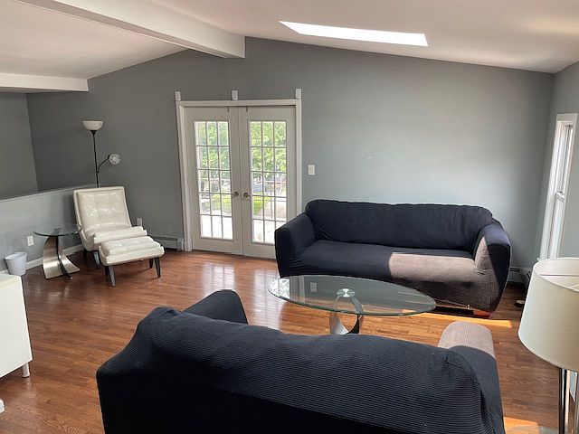 living room with cathedral ceiling and 2 skylights that opens up to large porch