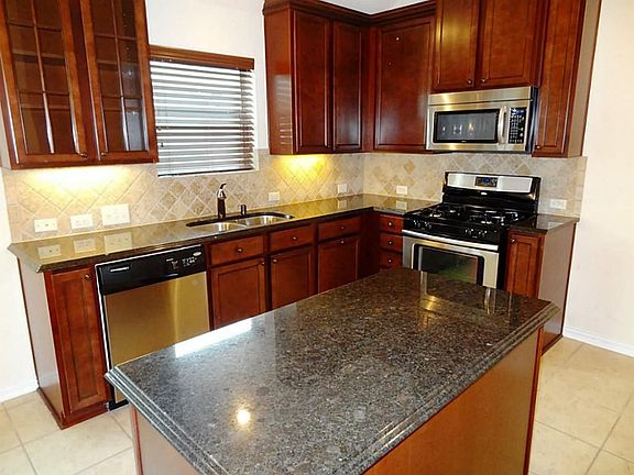 Island kitchen with granite, stainless steel appliances, gas range, custom back splash , tile floors