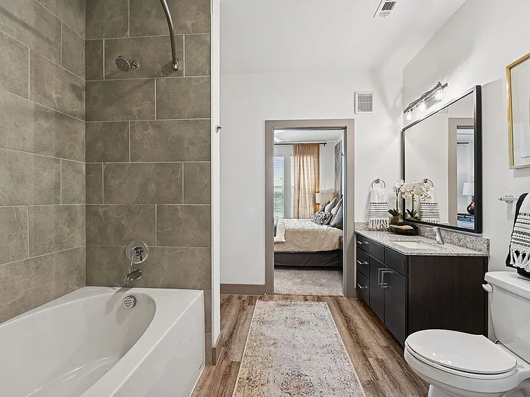 Bath with espresso cabinetry, speckled granite countertops, and hard surface flooring