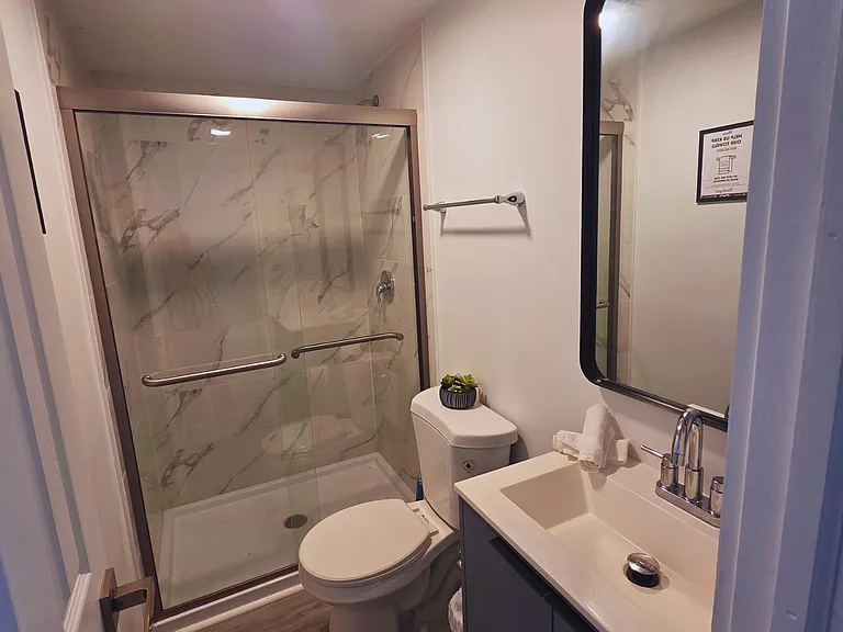 Spotless bathroom with toilet, shower, sink, and towel set