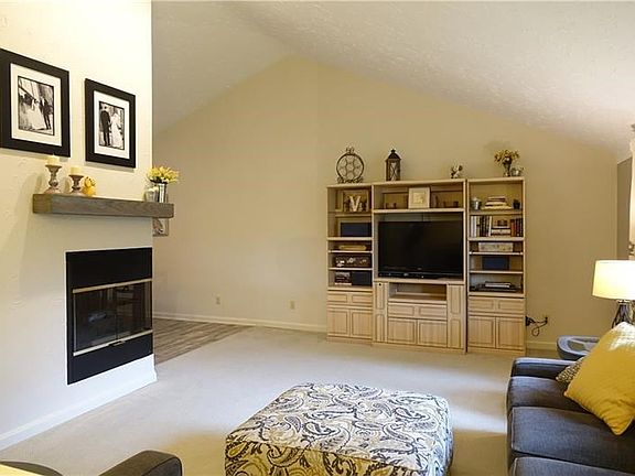 Living room with 3 way gas fireplace, vaulted ceiling, and newer carpeting