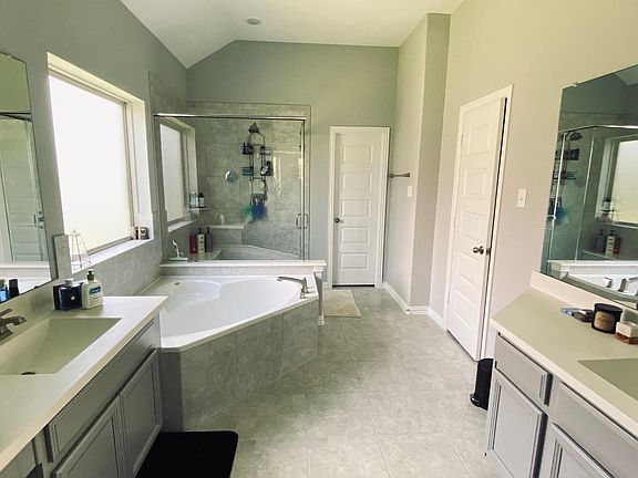 Master bathroom with dual facing faucets, oversized tub, and large walk in closet