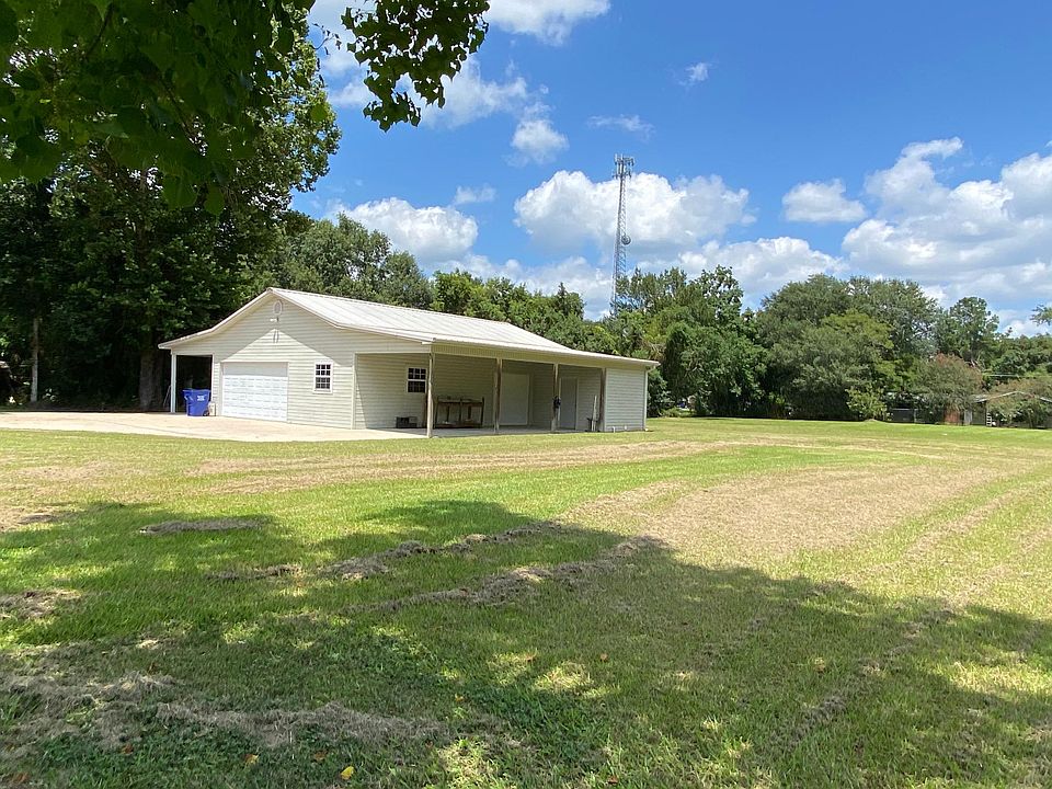 This is the view shows the yard and also the other side of carport. The large utility room entry door is here and the carport could be used as a patio. There is a second small garage door also under the carport that accesses the garage.