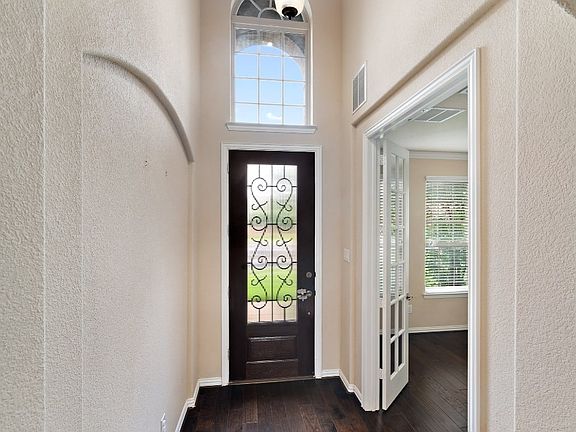 Foyer featuring dark wood-style flooring, a textured wall, and ornamental molding