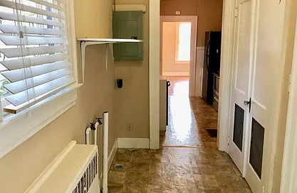 Mud hall looking through kitchen and into dining room (radiator, hookups, and bracket recently removed and hardwood laminate added to floor, plus white paint throughout)