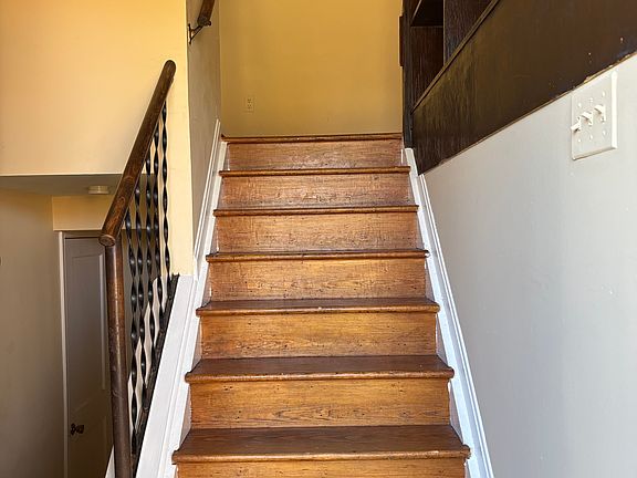 Entrance way showing split foyer with bookshelf lined staircase opening to vaulted ceiling.
