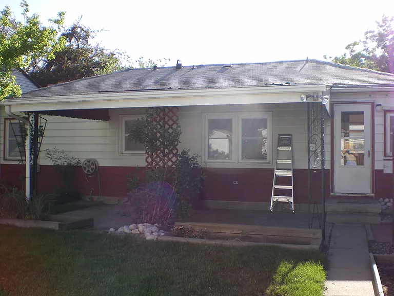 Backyard and patio during summer. From the left to right can view exterior door, Bedroom One windows, Bathroom window, and Bedroom Two.