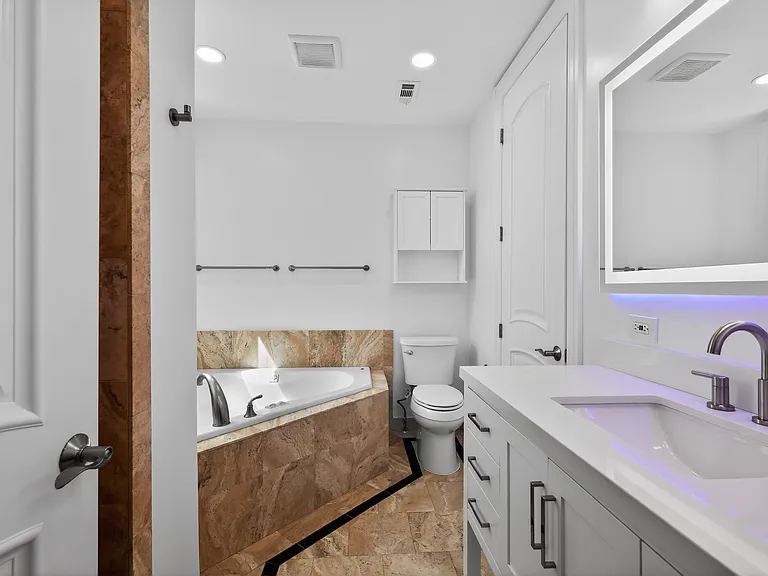 Master bath featuring full size triangular Jacuzzi, LED mirror (option to change colors) full shower with two shower heads, body jets and bench. Italian travertine throughout.