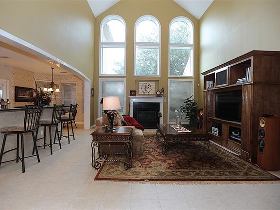 The living room has soaring ceilings, lovely arched windows, and is open to the spacious kitchen.