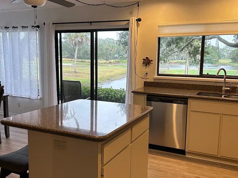 Kitchen and island with recessed lighting looking from dining room out to back patio