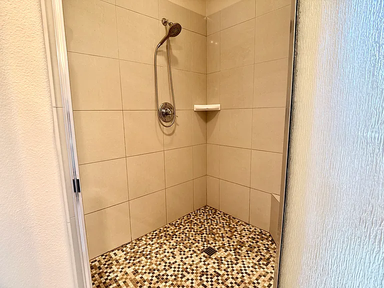 Tiled walk-in shower featuring an integrated tiled bench, thoughtfully designed to serve as both a comfortable seat and a functional storage ledge.