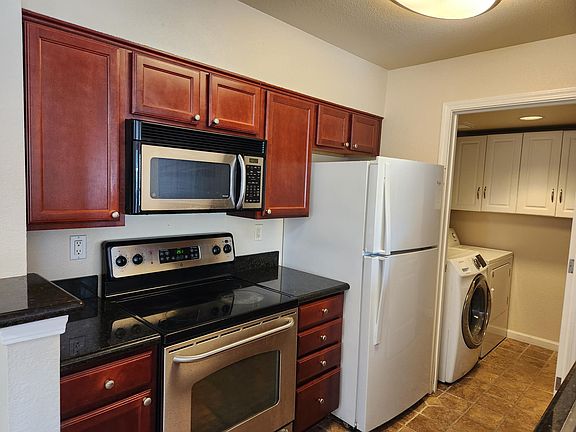 Cherry kitchen cabinets, stove, microwave and full- sized refrigerator
