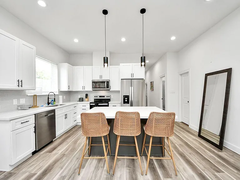 Spacious kitchen with a large island, bar seating, ample white cabinetry, and stainless-steel appliances for easy meal prep.
