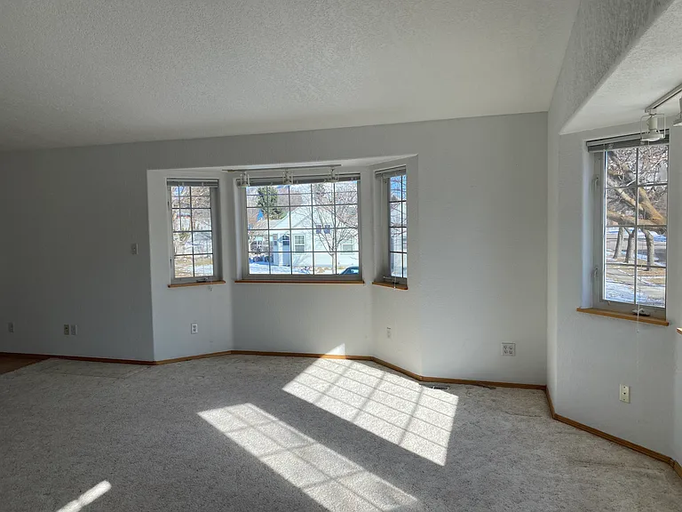 Spacious carpeted living room with vaulted ceiling and lots of light. Love the bay windows!
