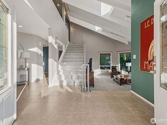 Bright and welcoming entryway with vaulted ceilings, large windows, and an open-concept layout.>