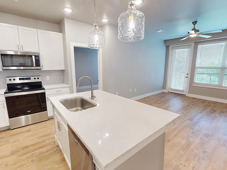Sling Station's living space includes wood-style flooring, pendant lighting, a large window, and patio/balcony access. Sling Station's living space includes wood-style flooring, pendant lighting, a large window, and patio/balcony access.