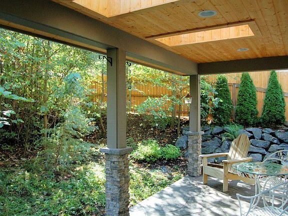Covered porch with skylights looks over a relaxing, leafy backdrop.