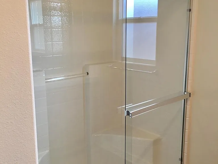 Master bathroom shower with glass sliding door is very clean.