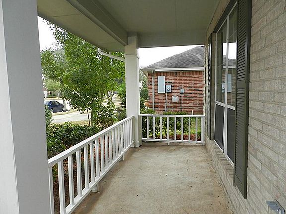 Extended covered front porch with wood railing.