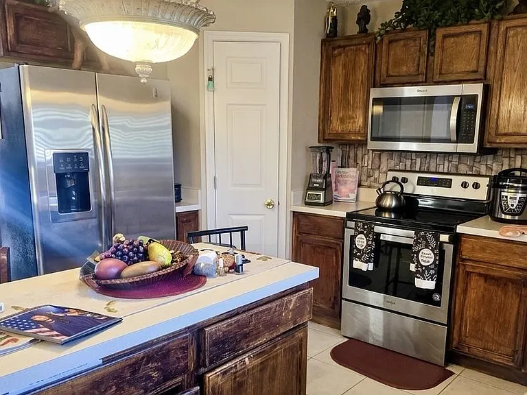 Functional kitchen with stainless steel appliances, ample wood cabinetry, and a central island for prep and seating.