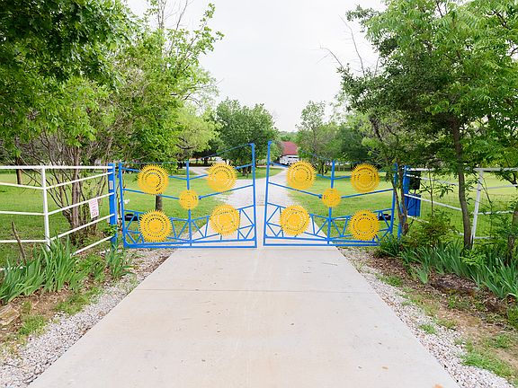 The property features a gated front entrance, leading to a paved cement driveway that offers a smooth, welcoming path right up to the house for added privacy and convenience.