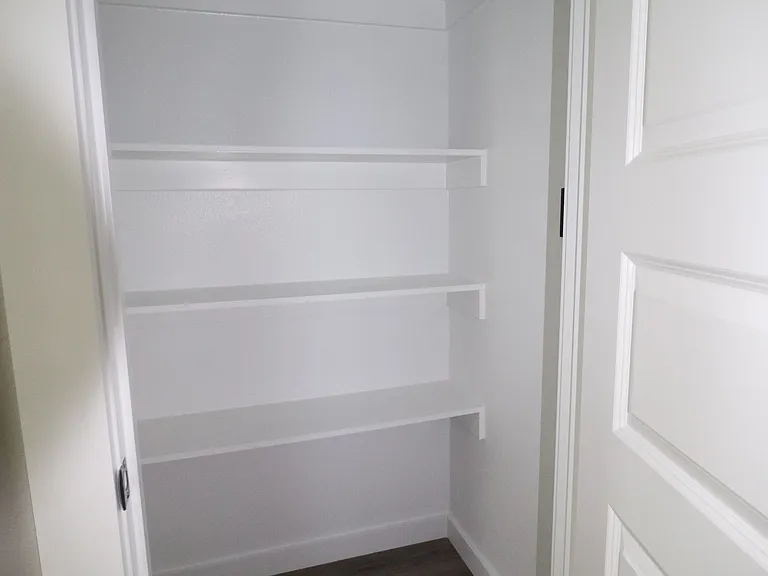 Spacious walk-in pantry offering ample shelving and storage, perfect for keeping the kitchen organized.