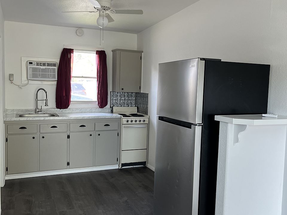Deep sink, commercial-style spray faucet, new stainless fridge, tin backsplash behind stove, farm-style kitchen details