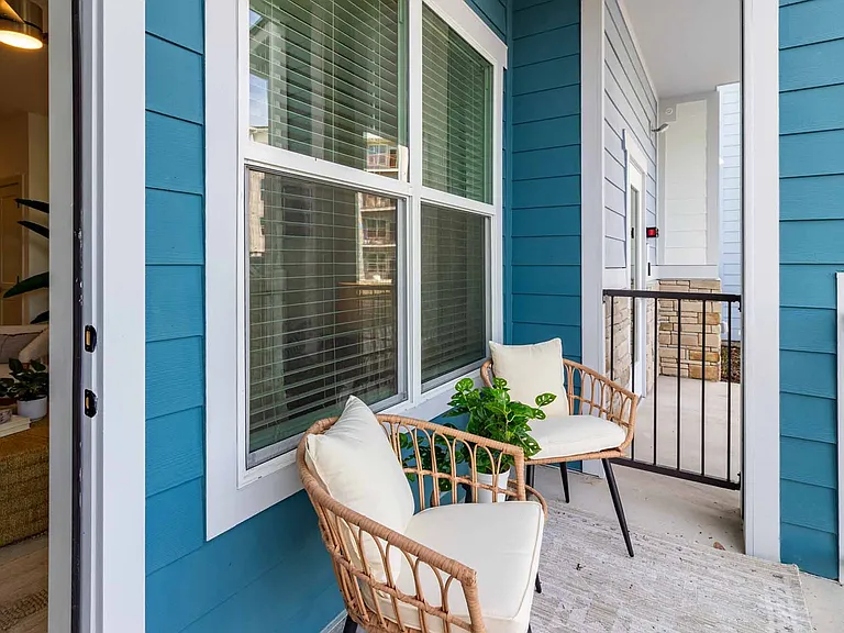Private balcony for outdoor relaxation, framed by the community's coastal blue exterior Private balcony for outdoor relaxation, framed by the community's coastal blue exterior