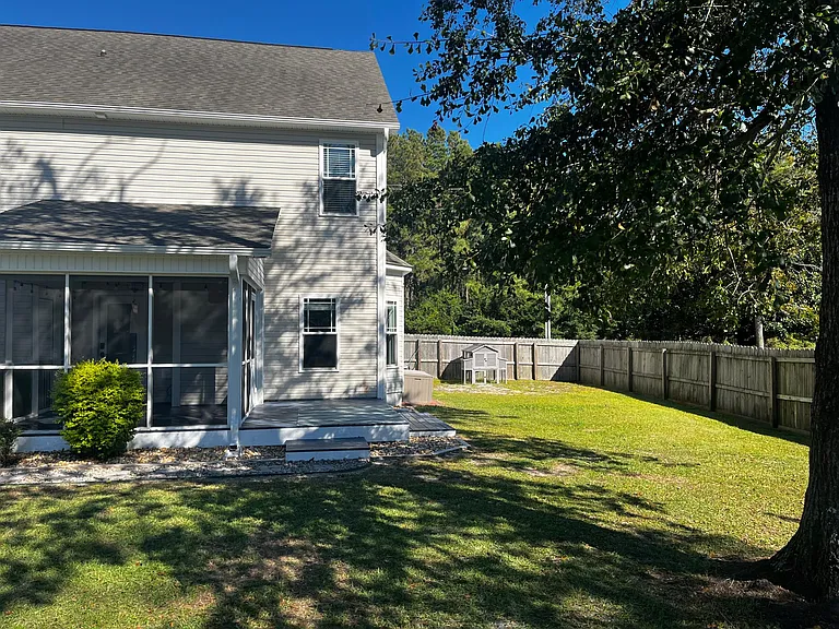 Side yard with fenced space, mature shade trees, and included chicken coop.