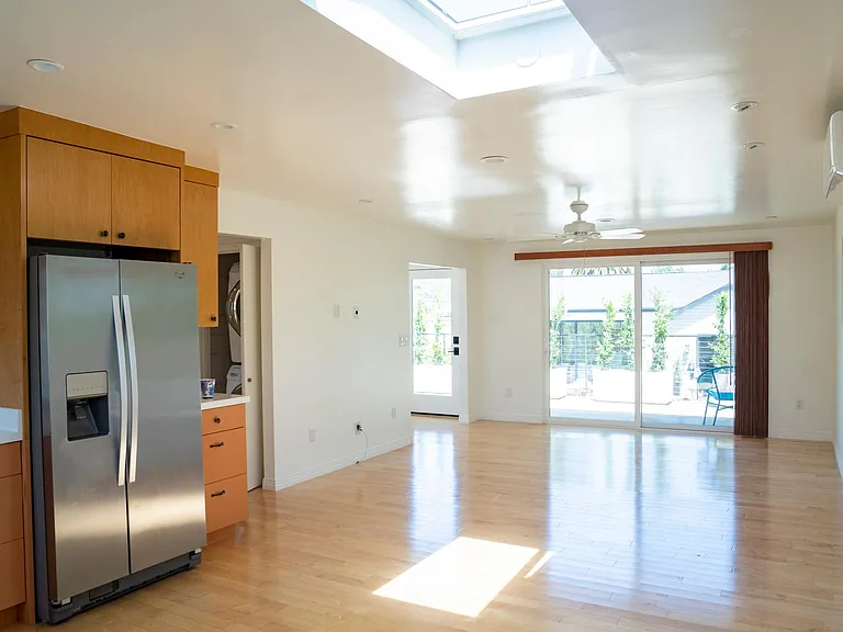 airy and bright living room with skylight and sliding door to patio