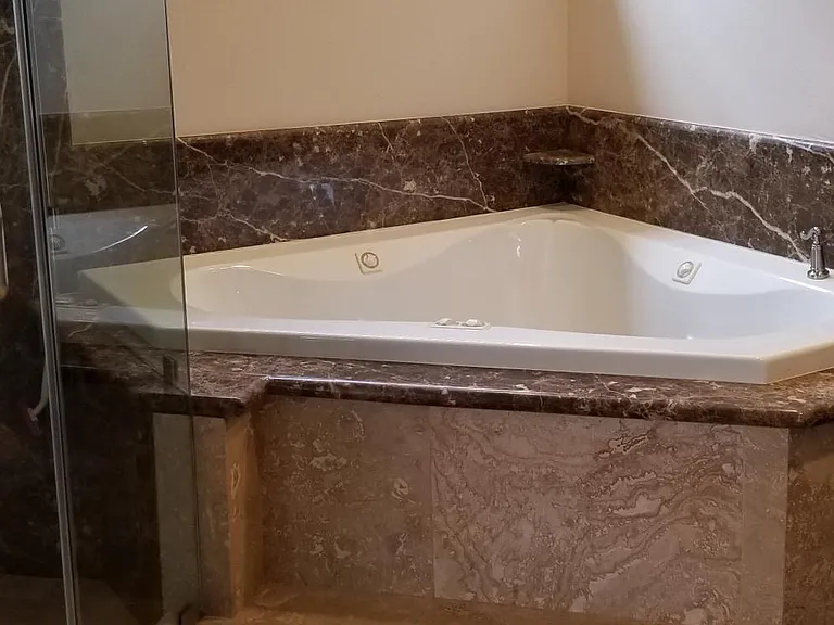 Master Bathroom Marble wall shower with Peruvian Travertine tile floors, seamless shower glass, and jacuzzi tub
