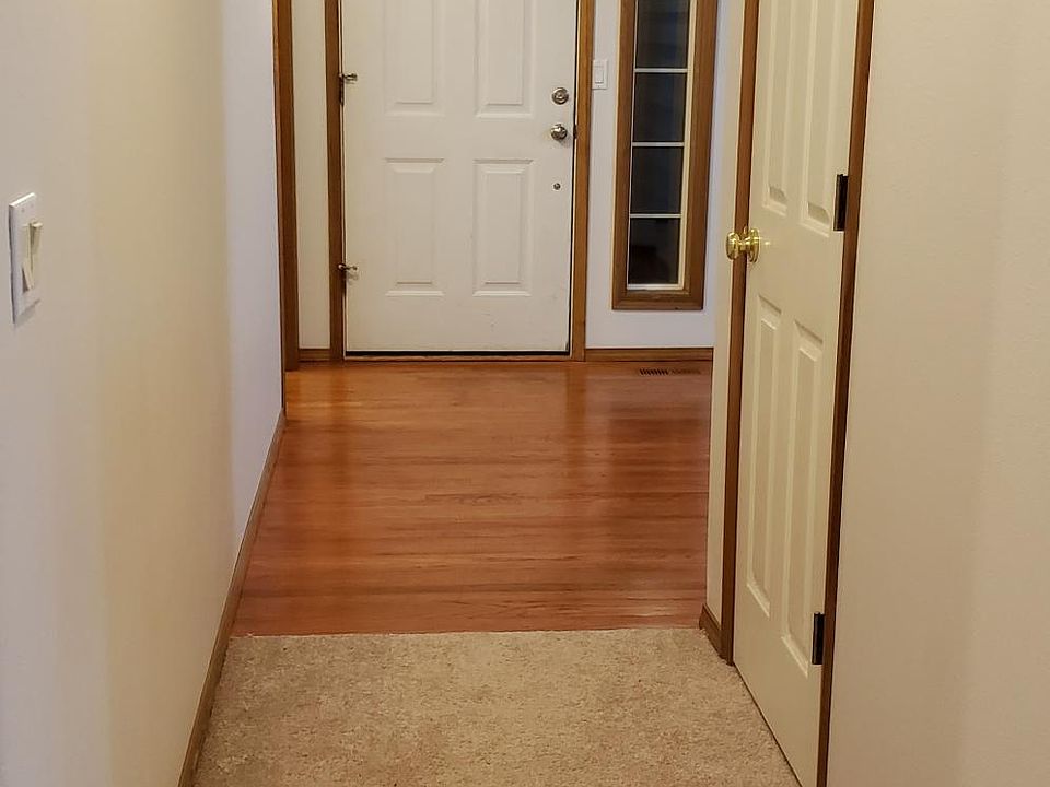 Front door viewed from bedroom hallway. Note hard wood floors. Laundry room is left of entry door with front room to right as viewed in picture. Kitchen is immediate right...note lighting on carpet from kitchen. Entry skylight not shown.