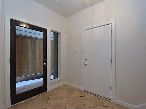 Glass front door with a small chandelier. The door leads to garage.