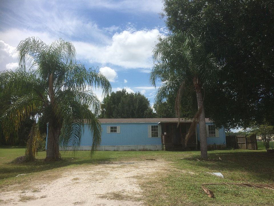 Front of home w/ palm trees and large driveway