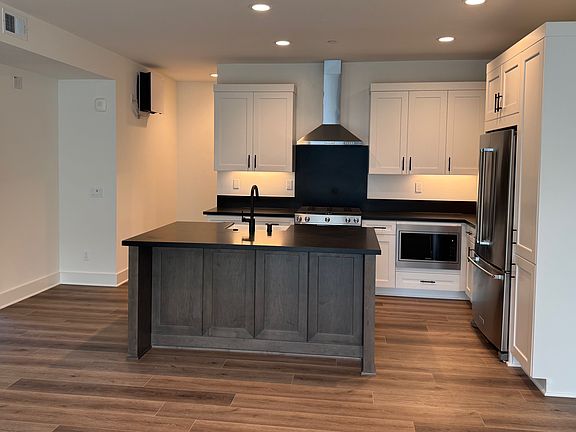 The kitchen sits on the opposite wall of the unique entryway.