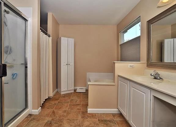 Luxury master bath with double bowl vanity, separate shower and deep soaking tub, ceramic tile floor