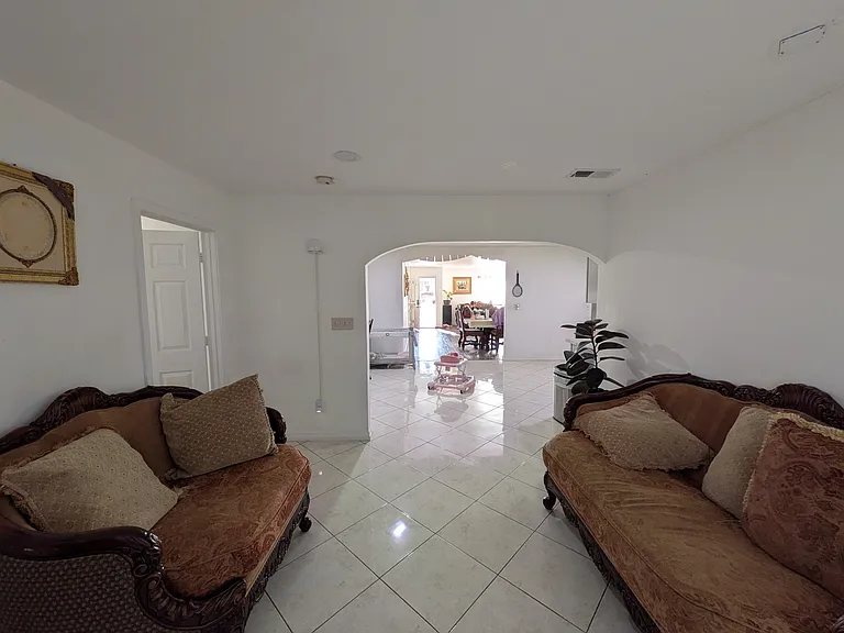 Shot from the backyard entrance facing the indoor kitchen, main entrance, and living/ dining area.