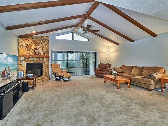 Living area with beamed cathedral ceiling and wood burning fireplace