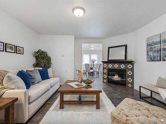 The living room features a ceramic-wrapped, gas-burning fireplace, easy-care flooring, and fresh paint. This place is perfect for cozy nights in Puyallup.>