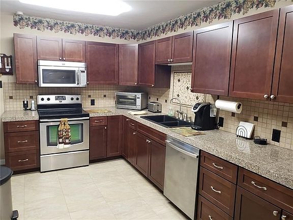 Large kitchen with stainless appliances, granite tile counter tops for meal prep, porcelain back splash & plenty of cabinets for
