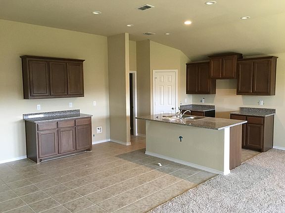 Beautiful open kitchen with premium cabinets, granite countertops, elevated ceiling, recessed light, island with stainless steel sink, and dining area with extra cabinets and counter space.