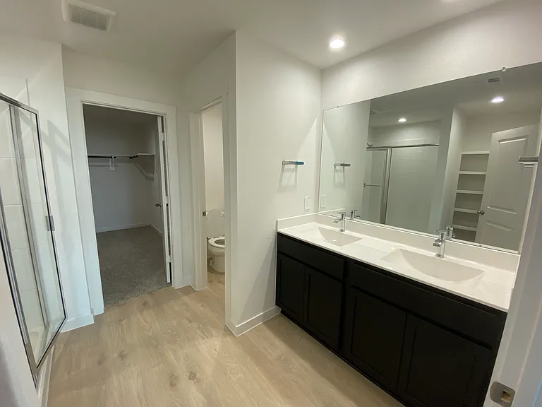 Master bathroom with two sinks and large shower, toilet with separate door
