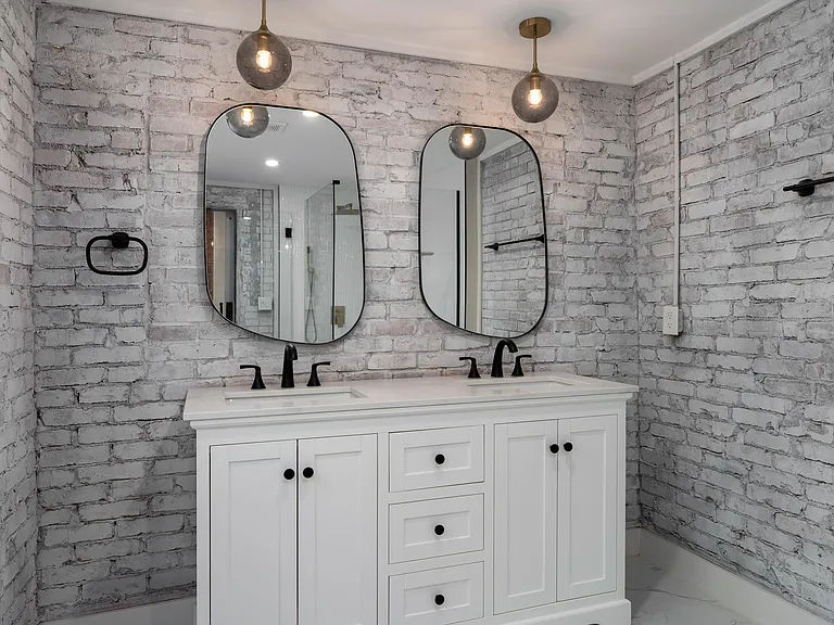 Updated bathroom vanity area with dual sinks, statement pendant lighting, and ample storage in the cabinet base.
