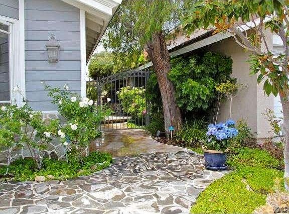 Flagstone walk in front leads to a gated courtyard entry.