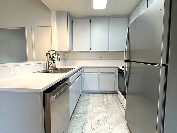 Kitchen with updated quartz countertop, brand new stainless steel dishwasher and refrigerator